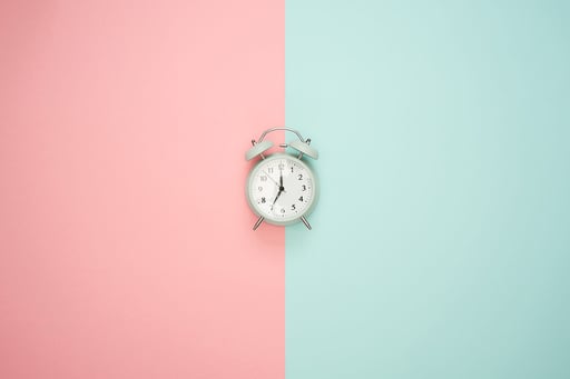 Alarm clock in front of pink and blue background