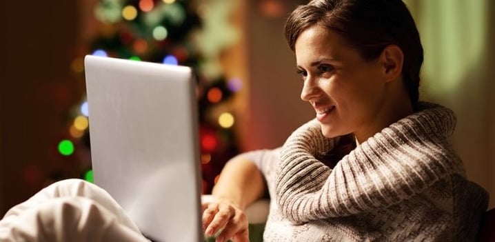 Woman on her laptop sitting in front of a Christmas tree
