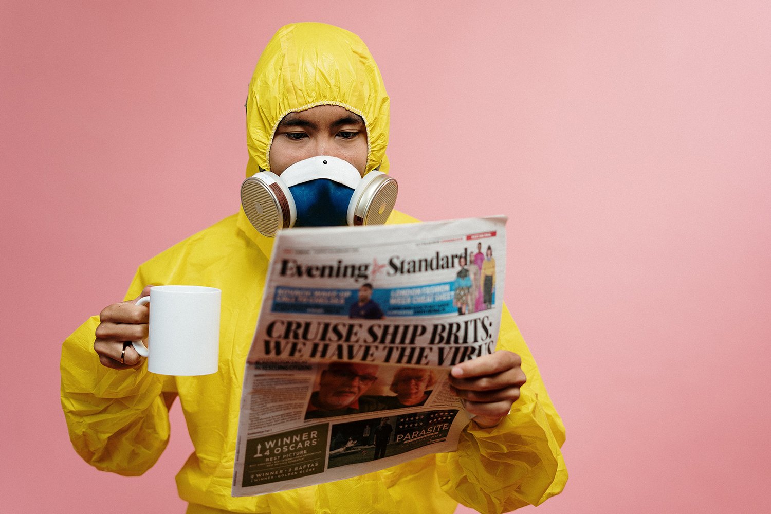 Man in hazmat suit drinking coffee and reading newspaper