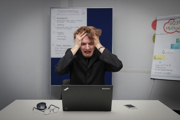 Stressed man sitting at computer pulling his hair