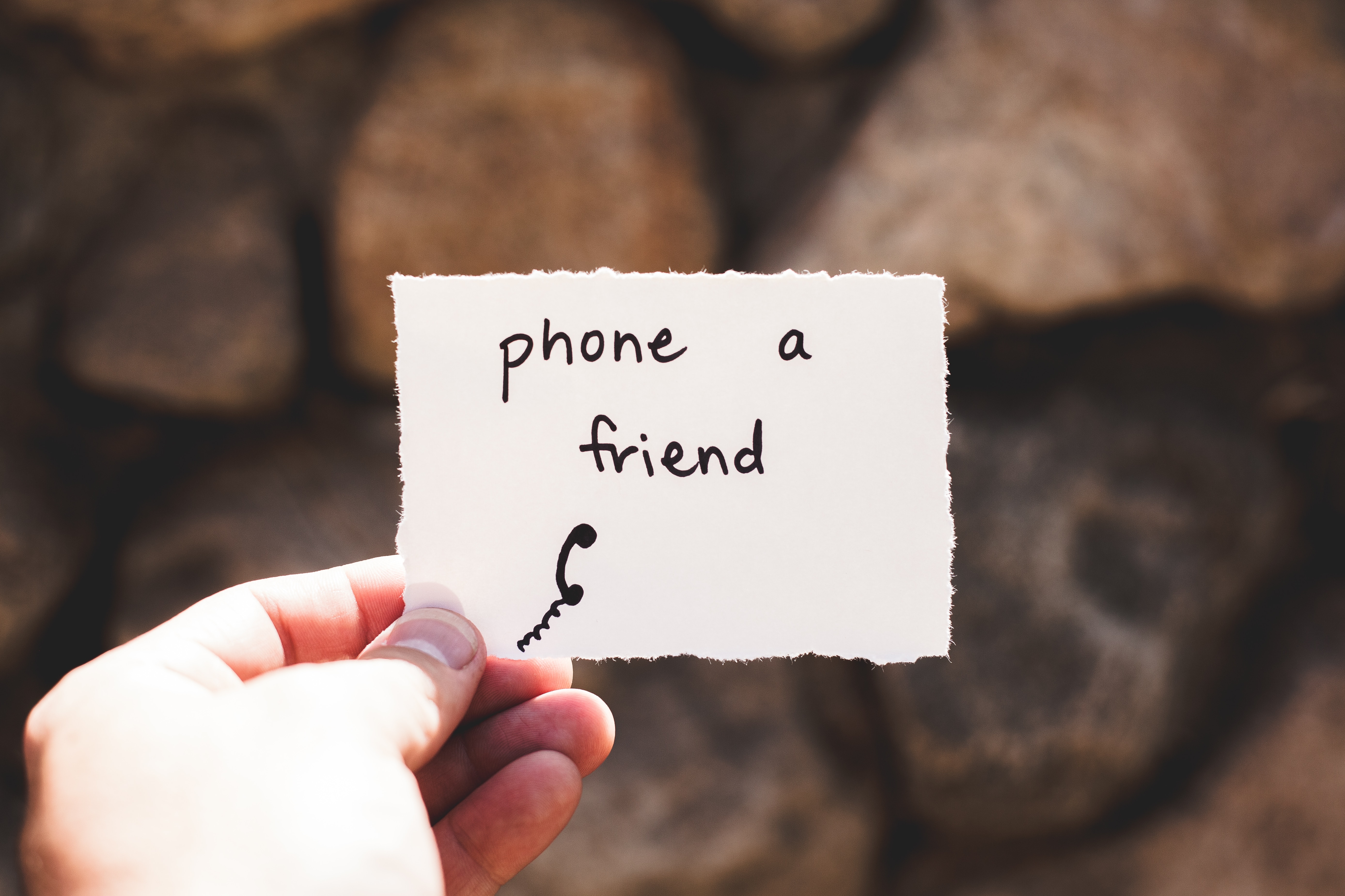 Hand holding a note that says "Phone a friend"